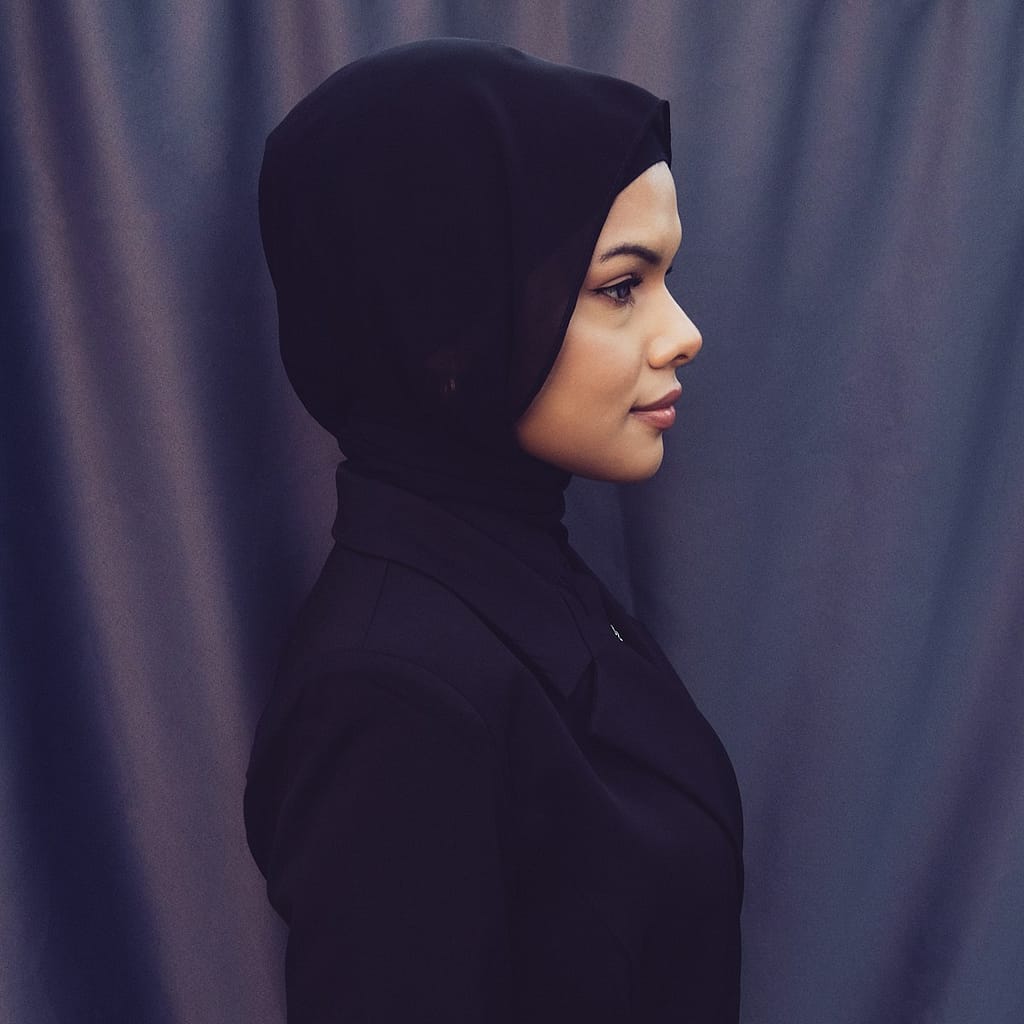 A woman in a black outfit standing in front of a curtain