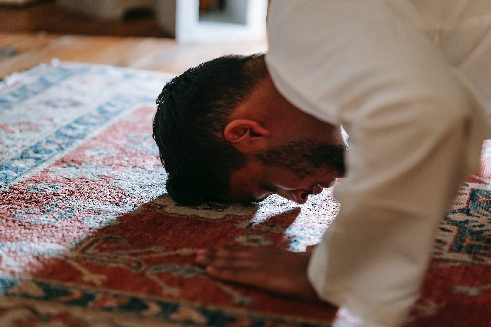 man in white dress shirt bowing down on a rug