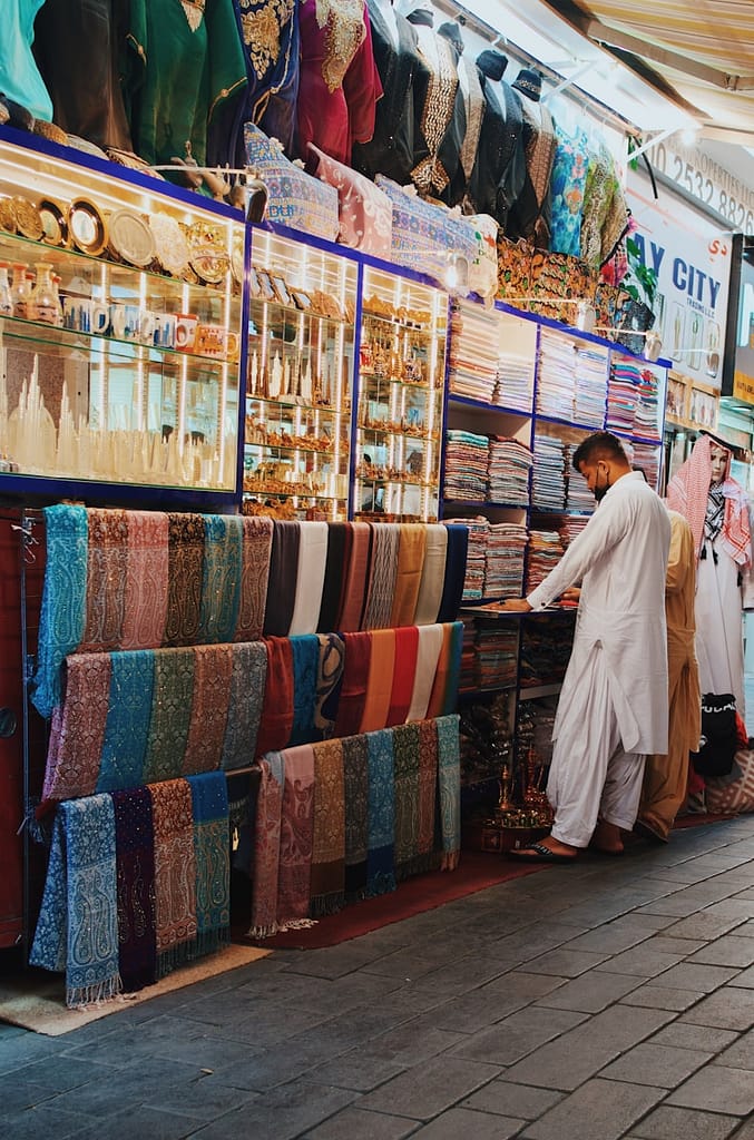 a man standing in front of a store filled with fabrics