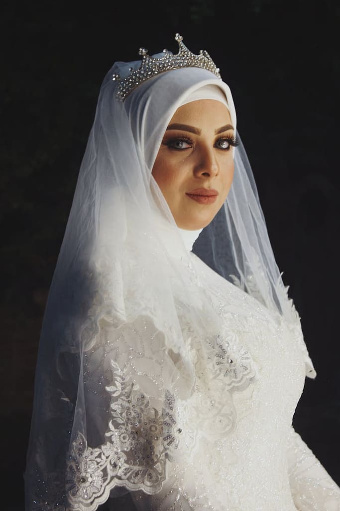 Elegant Muslim bride in hijab and veil standing in studio