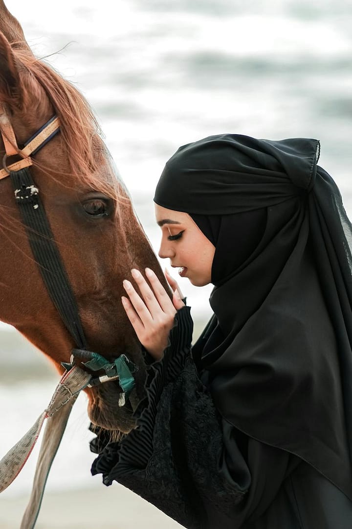 woman in hijab and abaya with horse
