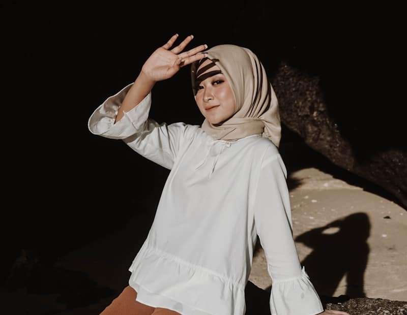 woman in white long sleeve shirt and orange pants standing on brown sand during daytime